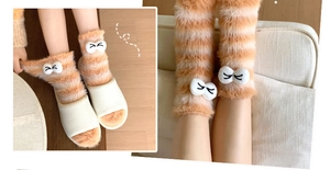 Detail of coral fleece thick winter socks featuring orange stripes and cartoon embroidery