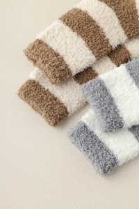 Close-up of thick coral fleece winter socks with striped pattern in soft coffee and grey