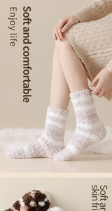 Close-up of soft striped coral fleece thermal socks on a cozy plush white carpet