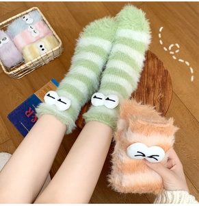 Close-up of cozy coral fleece socks with colorful stripes and 3D cartoon eye details