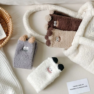 Detail of plush cartoon thermal socks in brown and gray with cute 3D ears embroidery