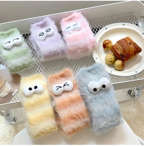 Detail of plush coral fleece socks in pastel colors with 3D cartoon eyes and soft texture