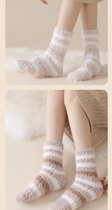 Detailed view of thick striped coral fleece warm socks worn on plush indoor carpet