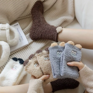 Close-up of thick coral fleece winter socks with cartoon monster embroidery and plush ears