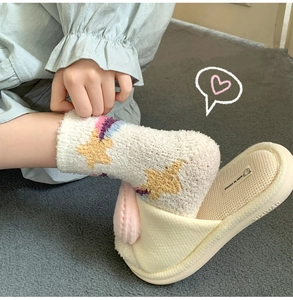 Detailed texture of thick coral fleece socks with yellow stars and rainbow wave patterns