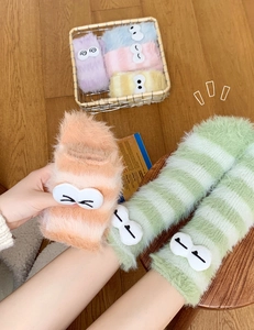 Detail of soft coral fleece striped socks with cute 3D cartoon eyes and fluffy texture