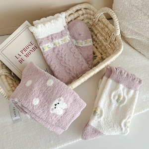 Pink and white fluffy coral fleece socks with floral embroidery in a cozy home setting
