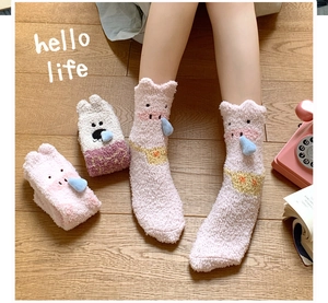 Detailed close-up of thick pink coral fleece socks with cute 3D blue nose on wooden floor