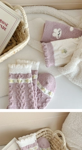 Detailed macro of thick purple coral fleece socks with cute bear embroidery and floral pattern