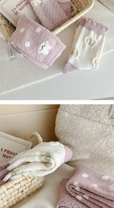 Close-up of thick thermal coral fleece socks with cute patterns in a woven basket