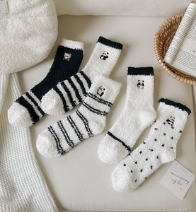 Close-up of cozy coral fleece socks with cute panda embroidery and striped patterns