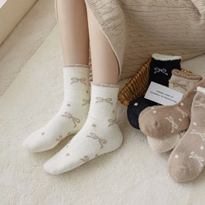 Detail of warm coral fleece socks with bow patterns and ruffle edges for winter