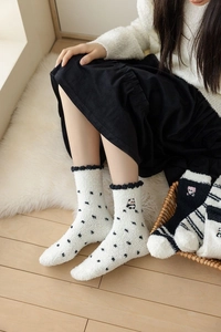 Detail of coral fleece winter socks with black polka dots and cute panda embroidery