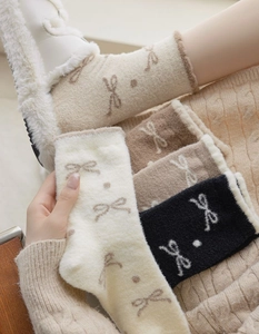 Close-up of thick winter socks with bow pattern in cream, brown, and black colors