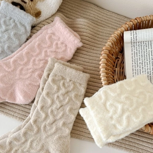 Close-up of thick winter knit socks featuring 3D heart patterns in soft pastel colors