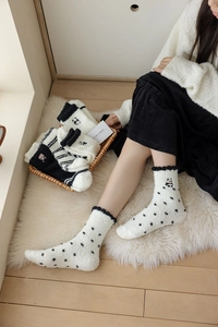 Detail of coral fleece panda socks with polka dots and stripes on soft white carpet