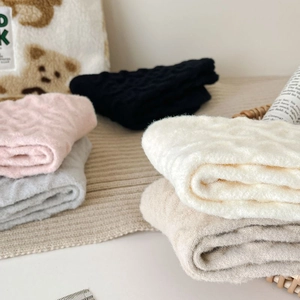 Detail of cable knit warm thermal socks in soft pastel colors on cozy home background
