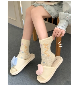 Close-up of cozy coral fleece socks with wavy patterns and plush open-toe slippers on feet