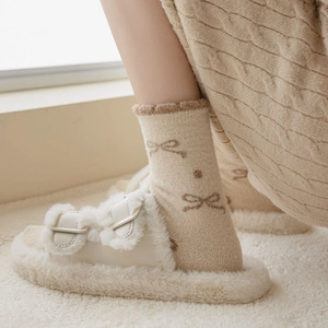 Detail of warm winter socks with bow pattern and ruffled cuffs in cozy home setting