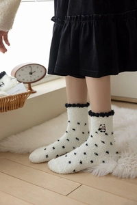 Detail of white coral fleece thermal socks featuring panda embroidery and black polka dots