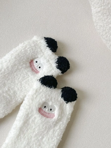 Detailed view of plush coral fleece fabric with cute cartoon embroidery and pompom ears