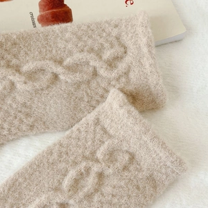 Detailed close-up of beige knit cable pattern socks with soft and fluffy plush texture