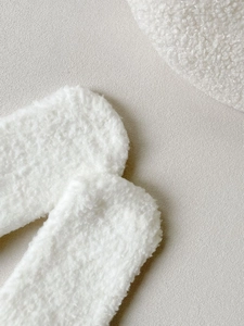 Macro shot of fluffy cream coral fleece fabric showing the thick soft texture of thermal socks