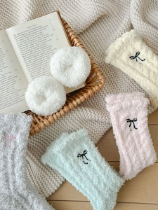 Dettaglio di calze invernali in pile corallo con ricamo fiocco nero e scrunchie peluche