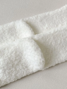 Close-up of white plush twist-knot headband made of soft coral fleece material