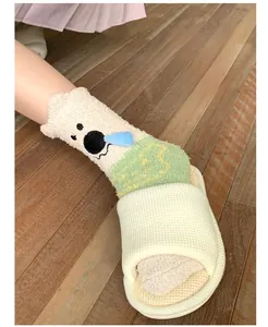 Close-up of cozy coral fleece socks with cute bear pattern and green accents