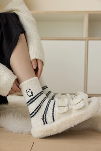 Detail of coral fleece socks with panda embroidery and plush slippers on a soft rug