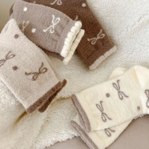 Close-up of thick plush winter socks featuring knitted bows and polka dots on fleece