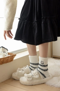 Detail of coral fleece panda socks paired with white plush platform slippers
