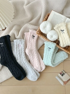 Dettaglio di calze invernali in pile corallo con ricamo a fiocco in colori pastello