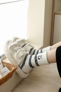 Detail of panda embroidery on striped coral fleece socks and white plush buckle slippers