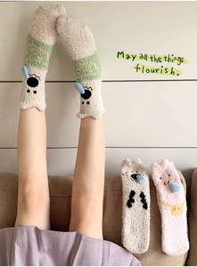 Detail of coral fleece socks featuring cute 3D cartoon animal faces and plush texture