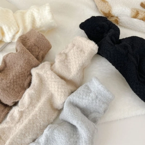 Thick warm fleece socks for women in beige grey and black on a soft plush background