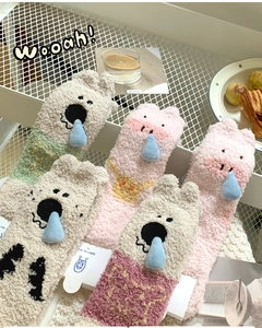 Detailed view of colorful coral fleece socks with cute animal 3D designs in a basket