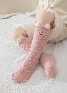 Détail de chaussettes roses en polaire corail avec broderie et oreilles mignonnes