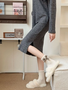 Detail of coral fleece socks with brown plaid bow accents and white plush slippers