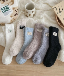 Close-up of thick coral fleece winter socks with cute bear labels in six soft colors