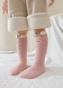 Détail de chaussettes thermiques en polaire corail rose avec broderie et pompons en 3D