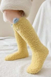 Gros plan de chaussettes en molleton corail jaune avec oreilles 3D et texture douce