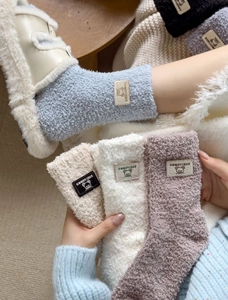 Detailed close-up of thick coral fleece winter socks with cute bear labels in soft colors