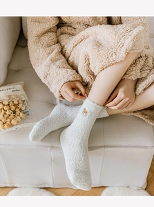 Close-up of cute bear embroidery on creamy white thick coral fleece winter socks