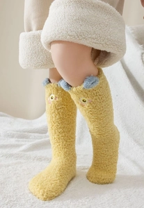 Gros plan de chaussettes en molleton corail jaune avec pompons bleus et broderies