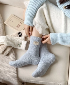 Detailed view of thick coral fleece socks with cute bear patch in cozy home setting