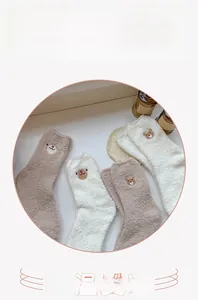 Close-up of thick coral fleece socks with cute bear embroidery for winter warmth