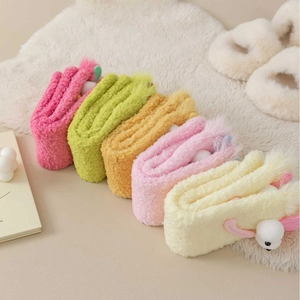 Plush coral fleece headbands in pastel colors with cute cartoon ears on a soft white rug