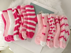 Close-up of assorted pink and white coral fleece socks set on a soft rug